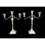 An associated pair of George VI silver three branch candelabra, with two white metal candle inserts,