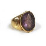 An amethyst intaglio inset within a 9ct gold signet ring, unmarked but tests as 9ct, with armorial