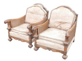A pair of early 20th century bergere armchairs, with walnut frames, a/f. (2) Damage to sides.