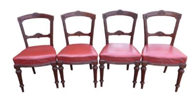 A set of four Edwardian mahogany dining chairs, with red leather upholstered seats, carved top and