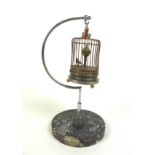 A novelty wind-up clock in the form of a bird in a cage, early 20th century, central rotating orb
