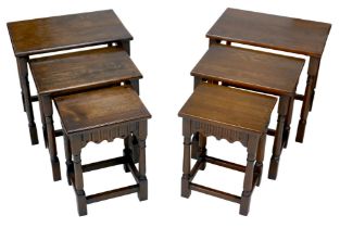 A pair of Old Charm style dark stained nests of three tables. (2)