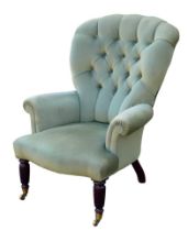 An Edwardian button back armchair, with green velvet upholstery, turned front legs and brass