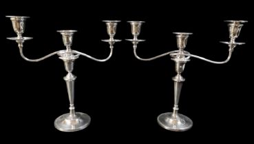 A pair of Elizabeth II silver twin branch candlesticks, with weighted bases and removable drip