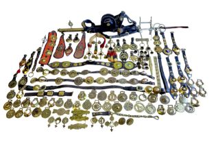 A collection of horse brasses, including Victorian examples, loose and on leather straps, together