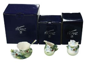 A collection of Franz porcelain ornaments in the Ladybug pattern, comprising a tea cup with spoon