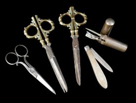 Two unusual pairs of 18th century scissors, possibly French, the brass handles cast with figures, on