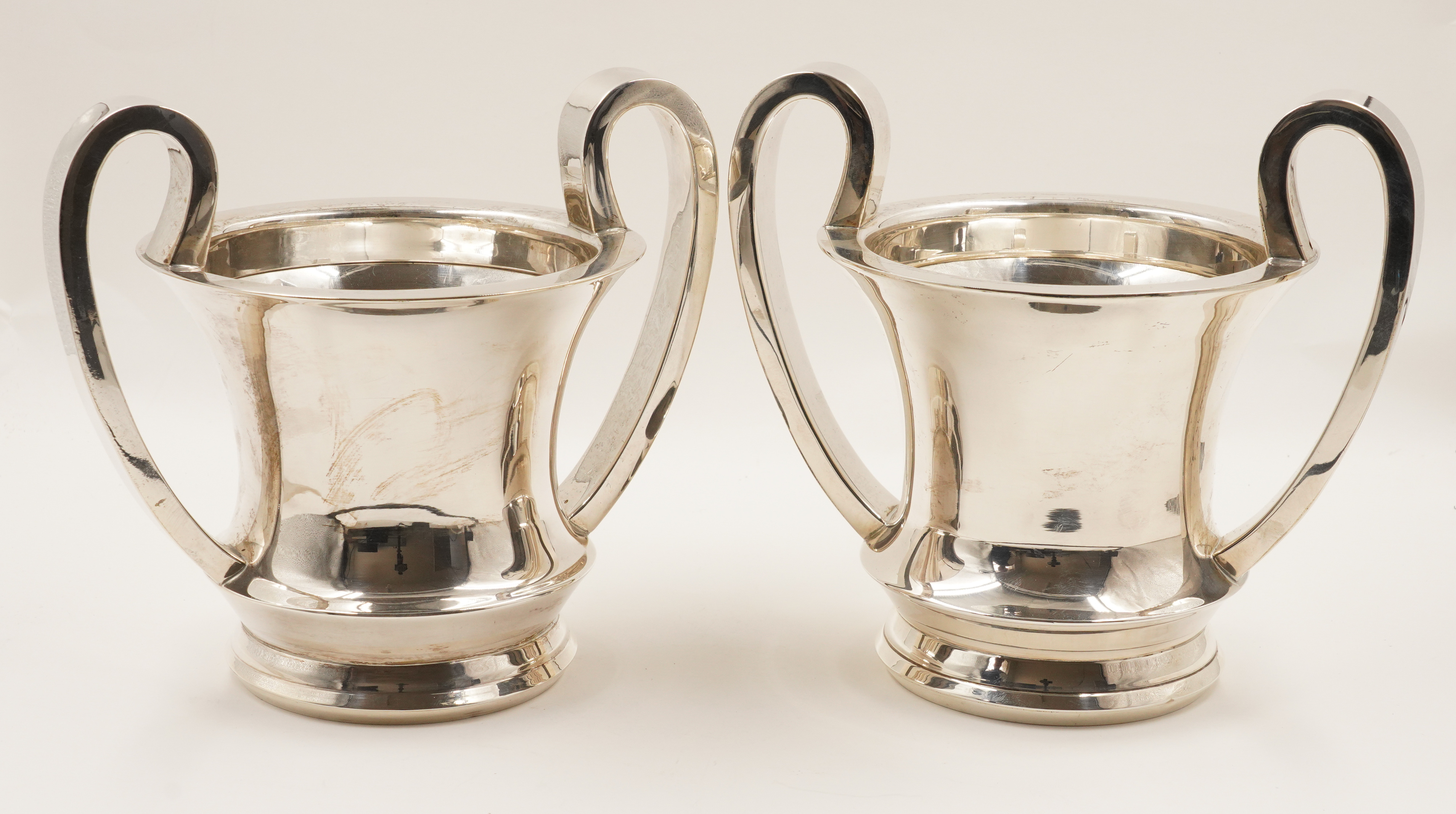 A PAIR OF SILVER TWIN HANDLED WINE BOTTLE STANDS