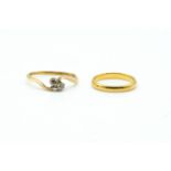 A DIAMOND TWO STONE CROSS OVER RING AND A 22CT GOLD BAND RING (2)