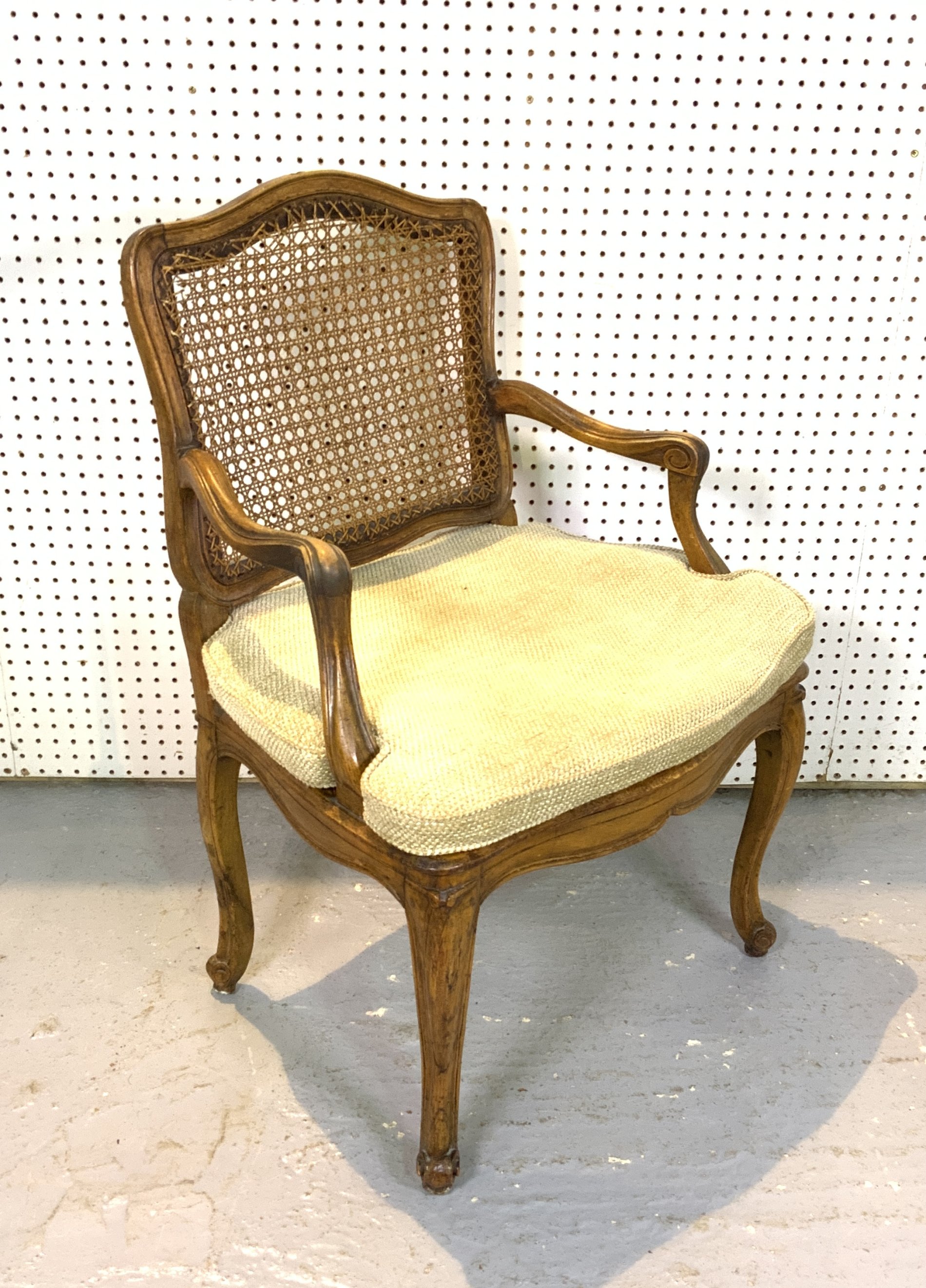 AN EARLY 19TH CENTURY FRENCH WALNUT AND CANEWORK OPEN ARMCHAIR