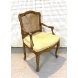 AN EARLY 19TH CENTURY FRENCH WALNUT AND CANEWORK OPEN ARMCHAIR