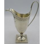 A Georgian style silver helmet cream jug on square base. Engraved decoration and monogram. Approx: