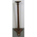 An Edwardian mahogany torchere, with carved and fluted column, on a triform base with bun feet.