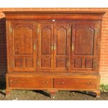 A large 18th century Welsh oak livery cupboard, the inlaid cornice featuring a central butterfly,