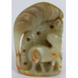 A Chinese carved pale green and russet Jade boulder, depicting an animal standing beside foliage,