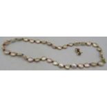 A pink 'disc' pearl necklace with small garnets between, on a 14ct yellow metal ball clasp, approx