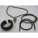 A black shark skin necklet with a large white metal pendant set with many precious & semi precious
