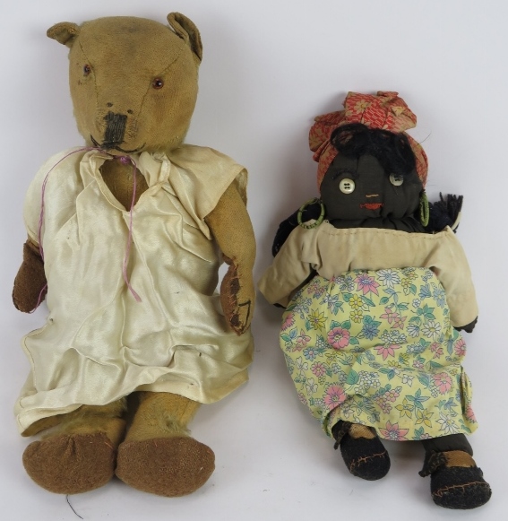 An early 20th century jointed Teddy Bear with growler in a silk nightdress and a handmade black