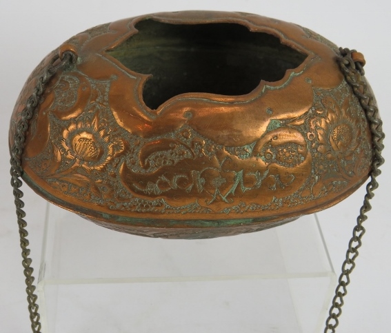 A small Middle Eastern copper Kashkul begging bowl with ornate chased decoration and chain handle.