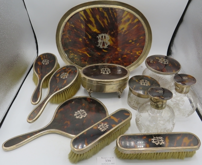 An 11 piece silver and tortoishell dressing table set. Comprising of jewellery box, 4 engraved glass