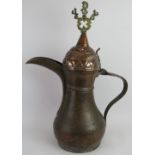 A very large Middle Eastern copper dallah coffee pot with ornate brass mounts. Height: 71cm.