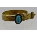 A yellow metal strap ring with turquoise coloured stone and black enamelling. 5grams. Condition