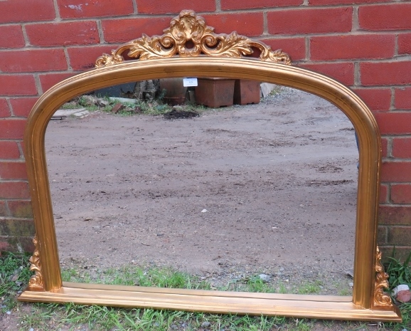 A 19th century style arched overmantel mirror in a gilt frame with moulded cornice and corner detail