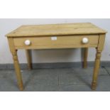 An antique stripped pine side table of small proportions, housing one long drawer with ceramic