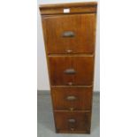 An early 20th century oak filing cabinet with fielded side panels, housing four drawers with cast