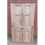 An antique stripped pine tall pantry cupboard, the top section with panelled doors opening onto