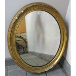 A vintage oval wall mirror in a moulded gilt gesso surround with beaded edging. H52 W44 D4 (approx).