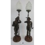 Pair of Auguste Poitevin Spelter figural table lamps on circular metal bases, glass flame globes,