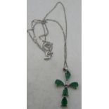 A 9ct white gold pear shaped emerald & single diamond cross pendant with a silver chain. Emeralds