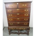 An 18th century oak chest on stand, housing two short over three long drawers with brass batwing