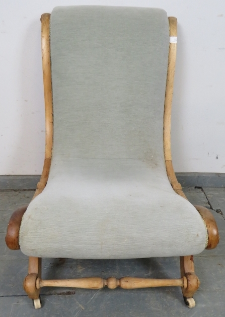 A Victorian beech slipper chair, upholstered in grey material with silver braiding, on scrolled