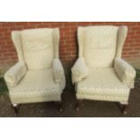 A pair of vintage Parker Knoll style wingback armchairs upholstered in foliate patterned cream