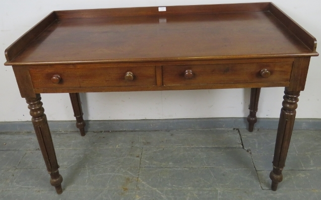A Victorian mahogany writing table, with 3/4 gallery, housing two short drawers with turned wooden