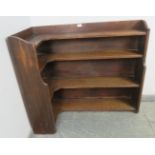 An early 20th century oak ecclesiastical low corner bookcase, of four graduated open shelves.