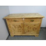 An antique stripped pine sideboard, housing two short drawers above a cupboard with loose shelf,