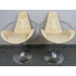 A pair of vintage mid-century swivel back stools, upholstered in buttoned cream leatherette, on
