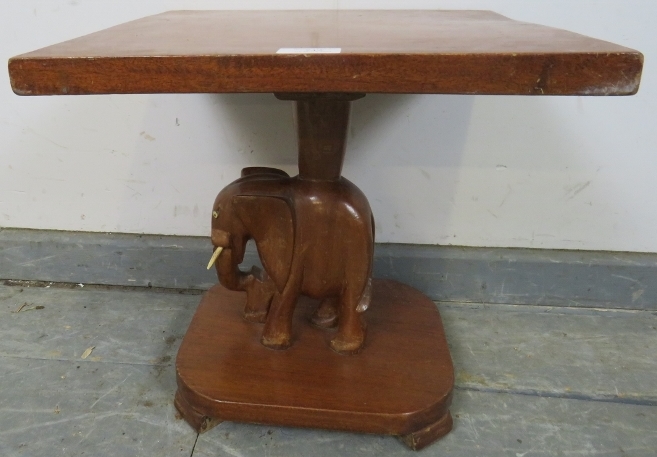 A vintage teak square table with carved stand in the form of an elephant, on a plinth base with