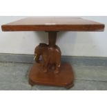 A vintage teak square table with carved stand in the form of an elephant, on a plinth base with