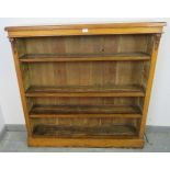 A Victorian golden oak low open bookcase, of three height adjustable shelves flanked by carved