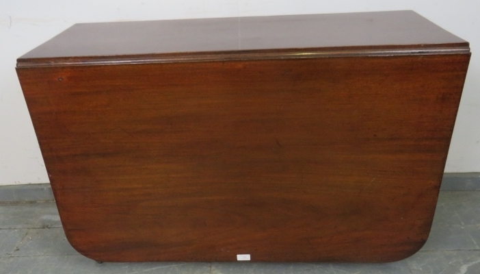 An early Victorian mahogany drop-leaf dining table, on tapering turned supports with brass caps