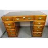 A vintage yew wood and brass bound campaign style pedestal desk, with inset green leather gilt
