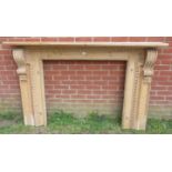 A large antique stripped pine fire surround, featuring egg and dart carved border and ornate corbels