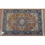 Small Persian rug central motif on reds and beige ground, within blue border. 97cm x 62cm. Condition