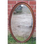 A large Victorian oval bevelled wall mirror in a carved walnut surround. H103cm W58cm (approx).