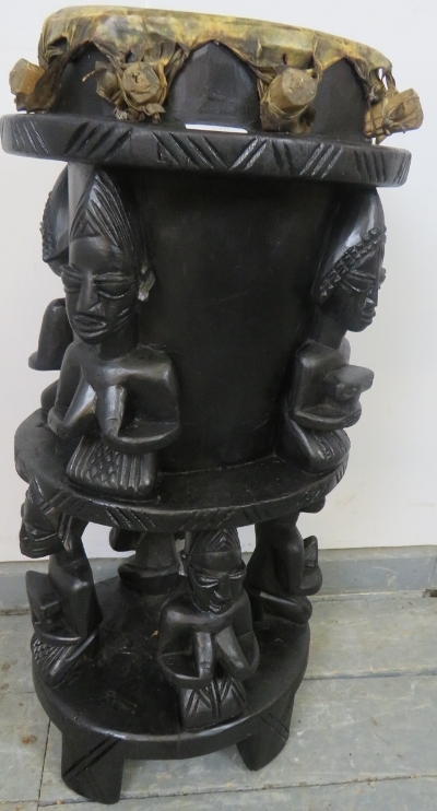 A vintage ebonised African tribal drum, carved with seated figures, on square supports. H71cm