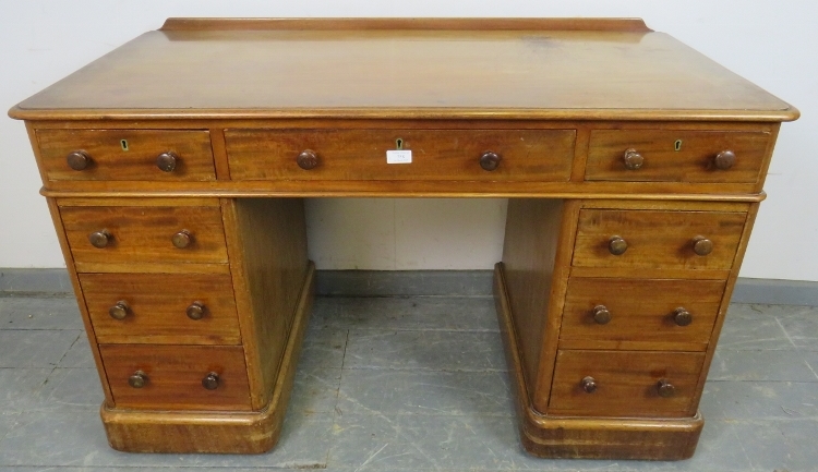 A Victorian mahogany pedestal desk, housing nine graduated drawers with turned wooden knob